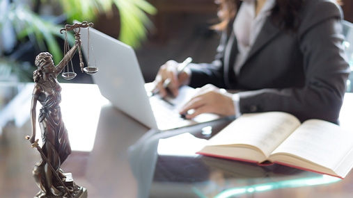 Female lawyer sitting at desk with laptop, book, and pen